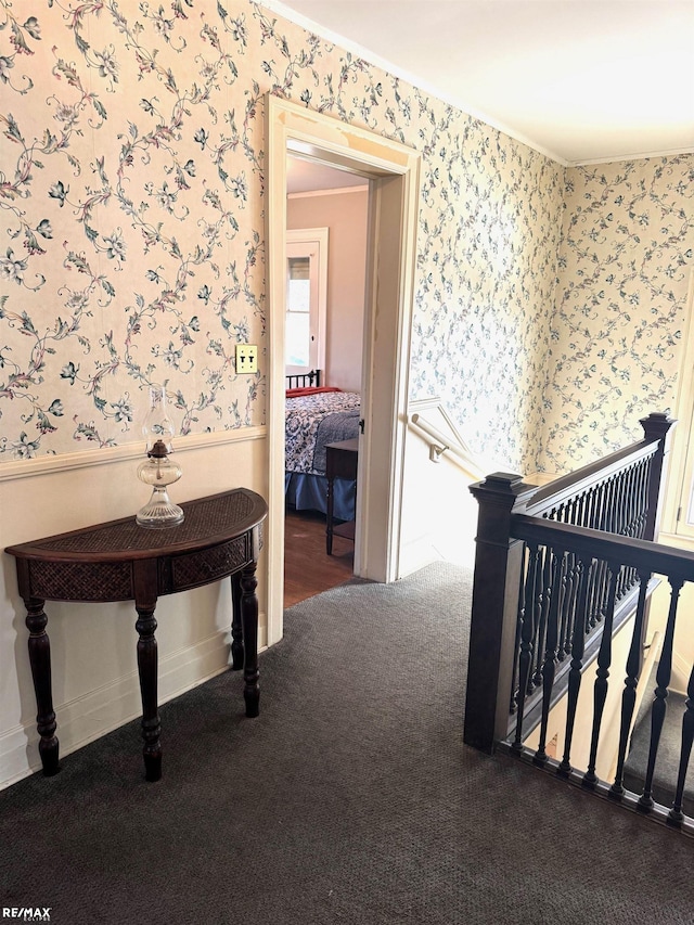 hallway featuring ornamental molding and dark colored carpet