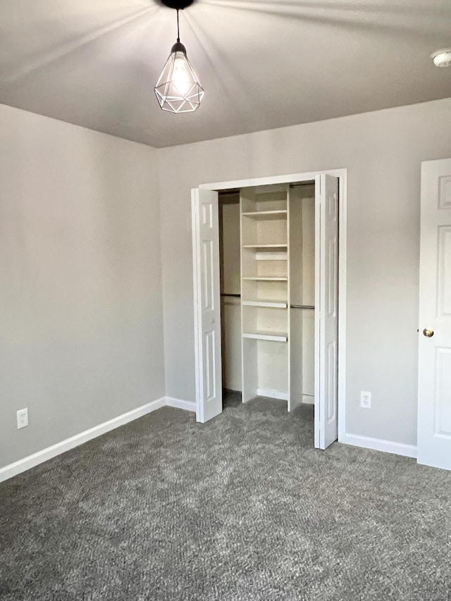 unfurnished bedroom featuring a closet and dark carpet