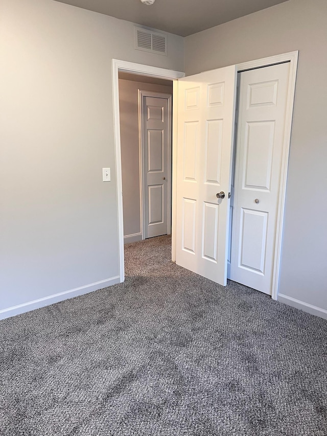 unfurnished bedroom featuring a closet and dark carpet