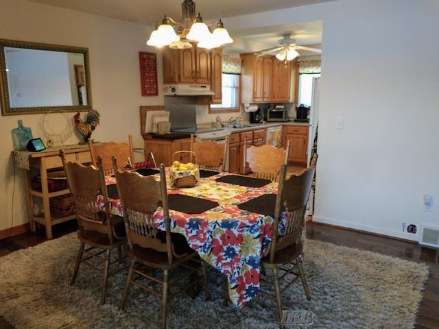 dining space featuring ceiling fan with notable chandelier, dark wood-type flooring, and sink