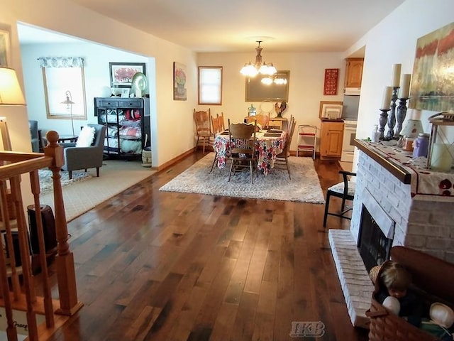 dining space featuring a brick fireplace, an inviting chandelier, and dark hardwood / wood-style floors