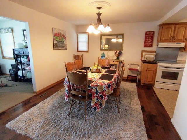 dining area with dark hardwood / wood-style flooring and an inviting chandelier