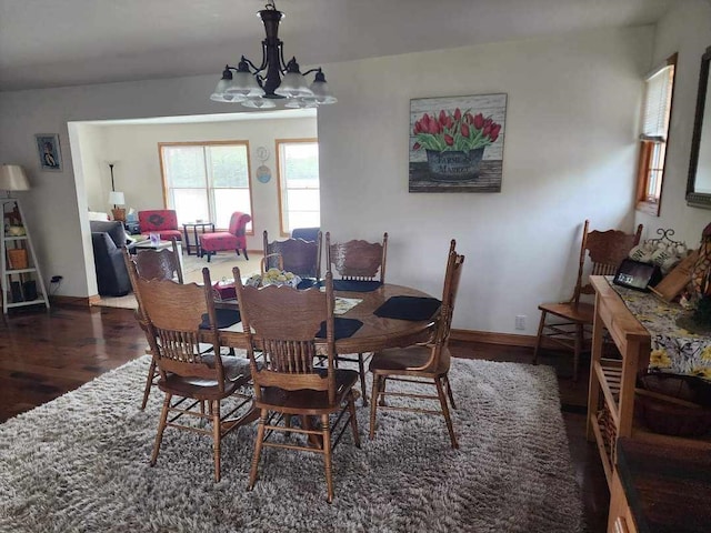 dining space with a notable chandelier and dark hardwood / wood-style flooring