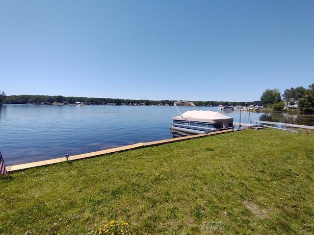 view of dock with a lawn and a water view