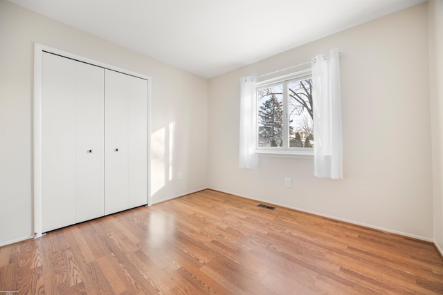 unfurnished bedroom with light hardwood / wood-style flooring and a closet