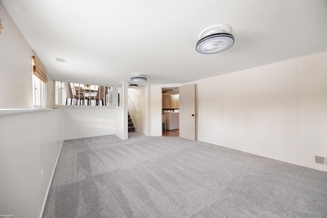 spare room featuring washer / clothes dryer and light carpet