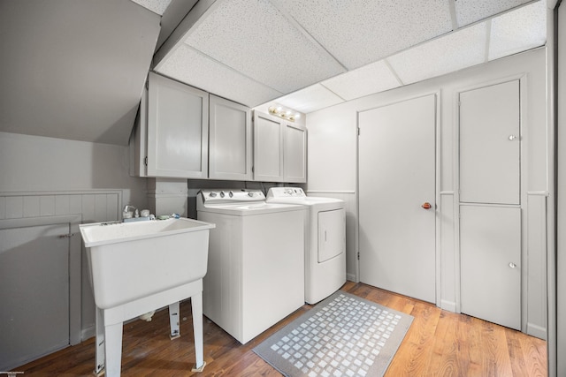 washroom with light hardwood / wood-style floors, cabinets, and washer and clothes dryer