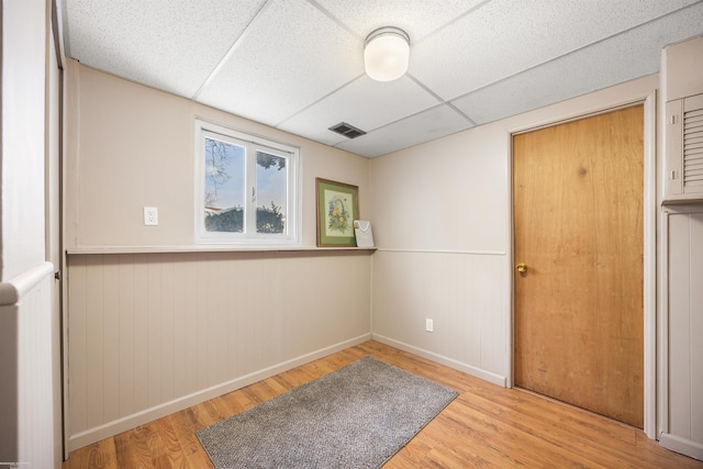 unfurnished room featuring a drop ceiling and light wood-type flooring