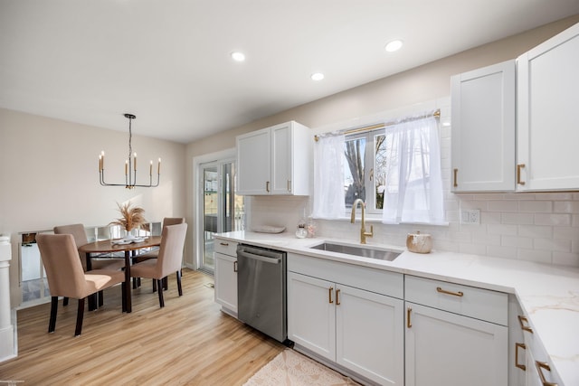 kitchen featuring stainless steel dishwasher, decorative light fixtures, light wood-type flooring, white cabinetry, and sink