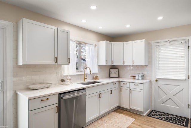 kitchen featuring white cabinets, stainless steel dishwasher, tasteful backsplash, and sink