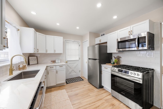 kitchen with sink, decorative backsplash, white cabinetry, and appliances with stainless steel finishes