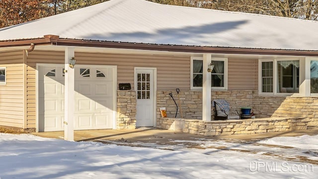 snow covered property entrance with a garage