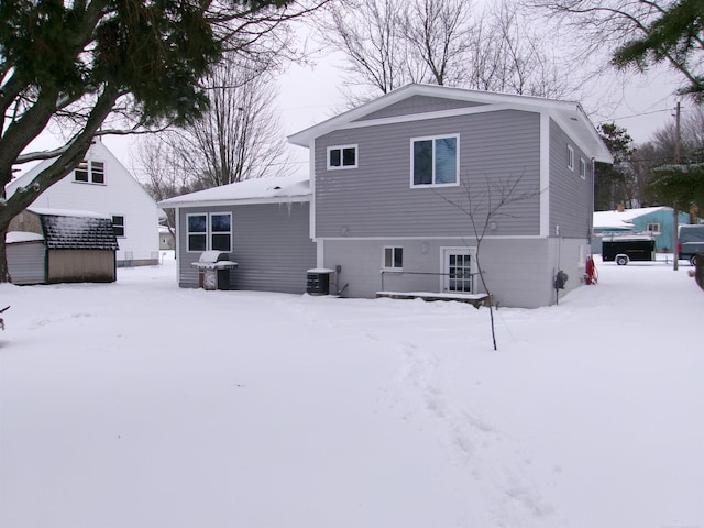 snow covered back of property featuring central AC unit