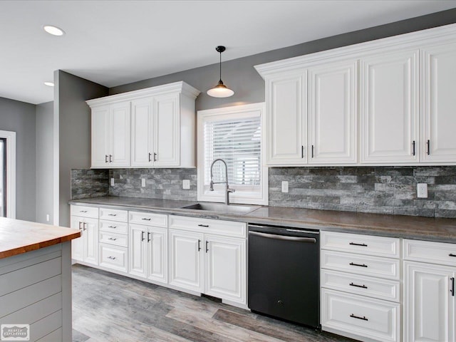 kitchen featuring backsplash, sink, black dishwasher, hanging light fixtures, and white cabinets