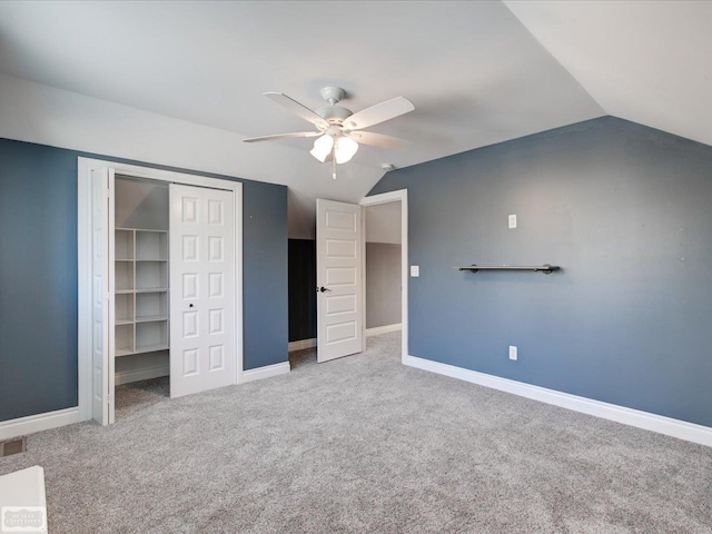 unfurnished bedroom with ceiling fan, vaulted ceiling, a closet, and carpet flooring