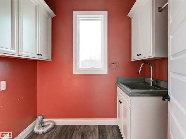 clothes washing area featuring cabinets, sink, and dark hardwood / wood-style flooring