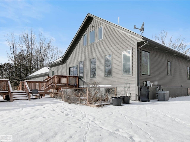 snow covered property with a wooden deck and cooling unit