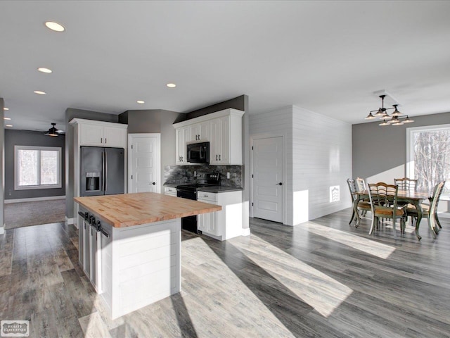 kitchen with white cabinetry, black appliances, a center island, and wooden counters