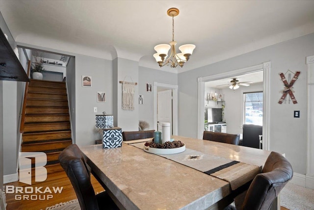 dining space with ceiling fan with notable chandelier and hardwood / wood-style floors