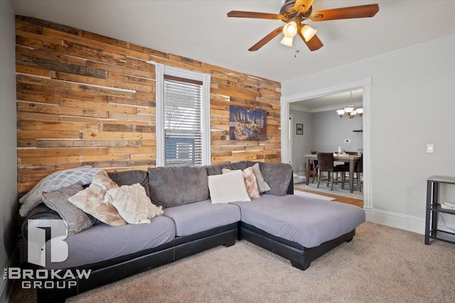 living room with ceiling fan with notable chandelier, wood walls, and carpet