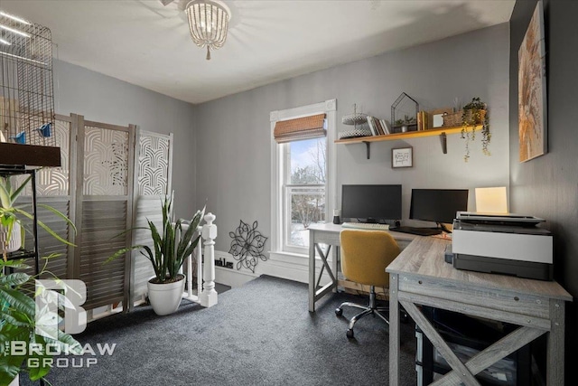 carpeted home office with an inviting chandelier