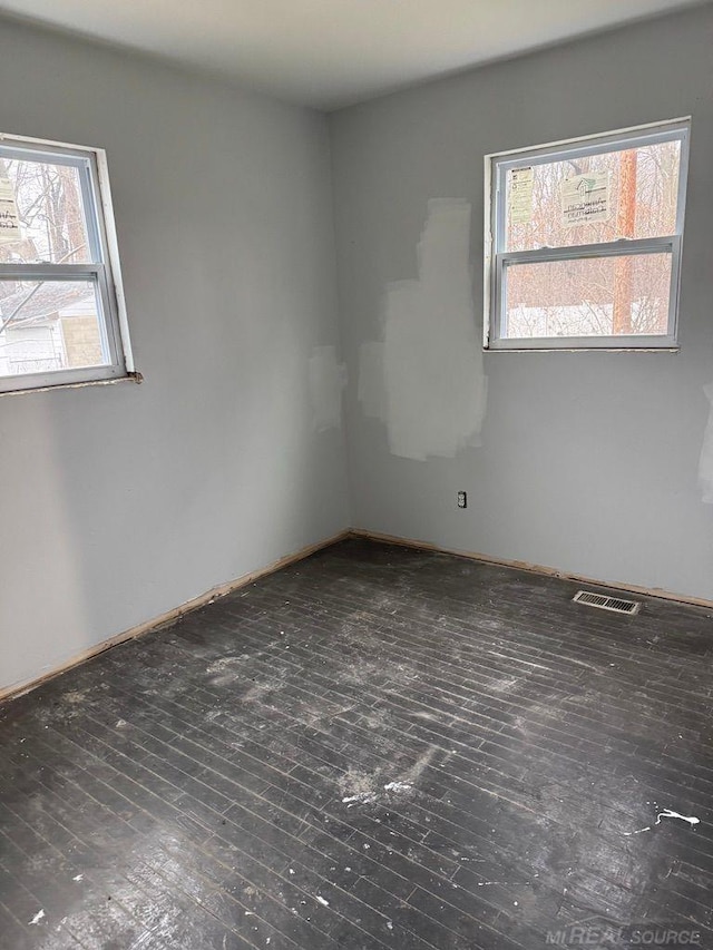 empty room featuring a healthy amount of sunlight and dark hardwood / wood-style floors