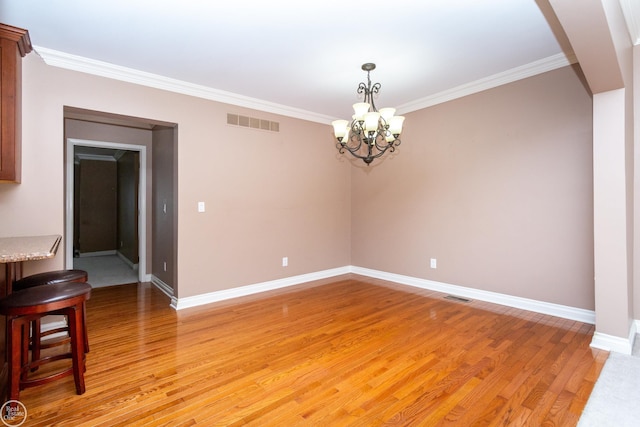 empty room featuring light hardwood / wood-style floors, crown molding, and a chandelier