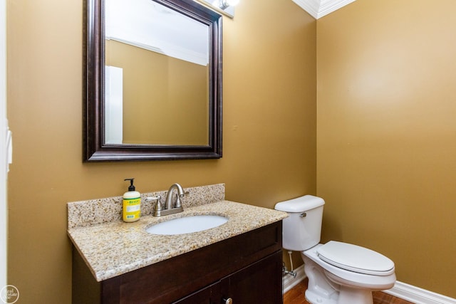 bathroom with toilet, ornamental molding, and vanity