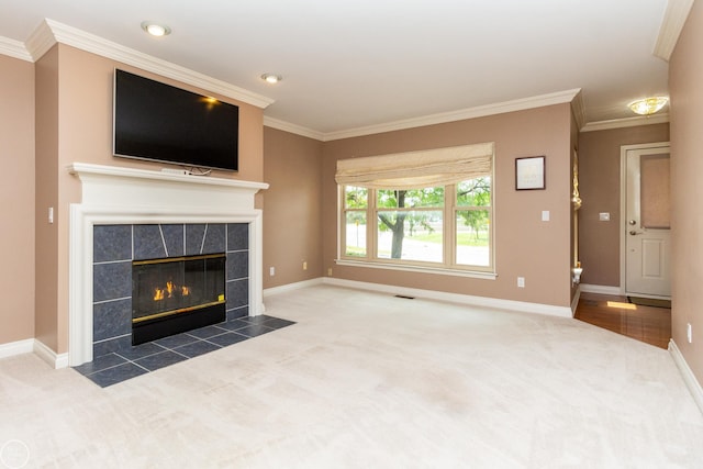 unfurnished living room with a tiled fireplace, ornamental molding, and carpet flooring