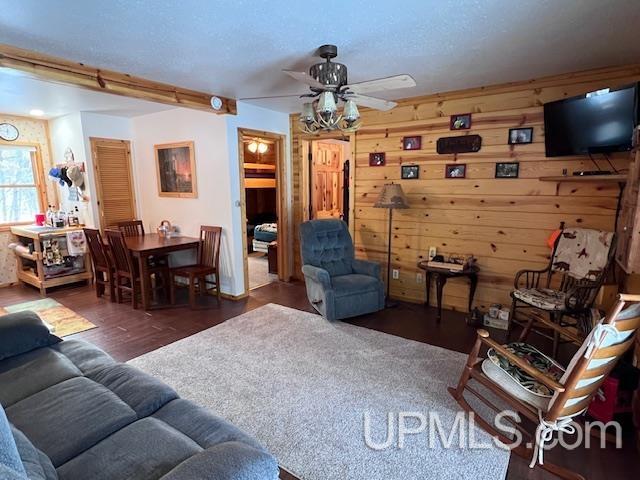 living room featuring wood walls, ceiling fan, and dark hardwood / wood-style floors