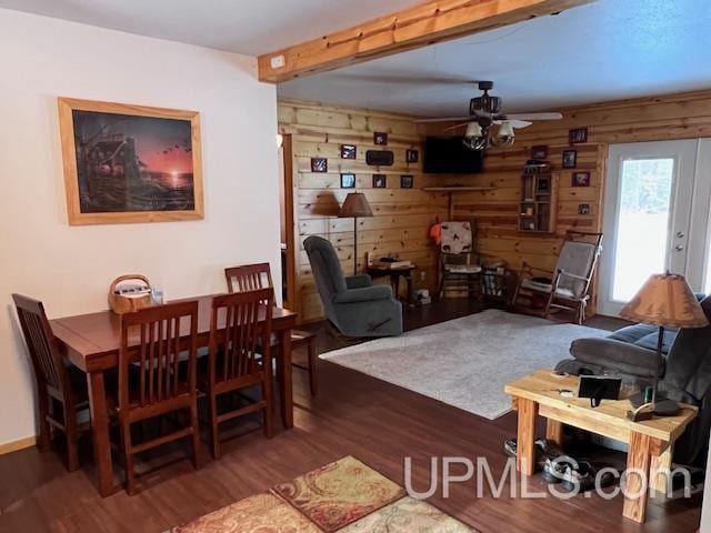 dining room featuring hardwood / wood-style flooring, wood walls, ceiling fan, and beamed ceiling