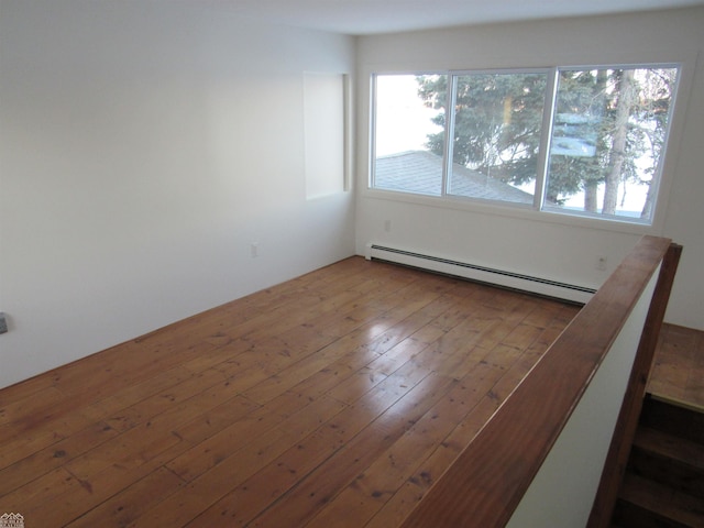 empty room featuring a baseboard heating unit and hardwood / wood-style flooring