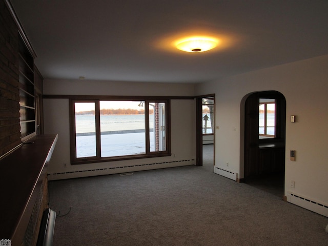 carpeted spare room featuring a healthy amount of sunlight and a baseboard radiator