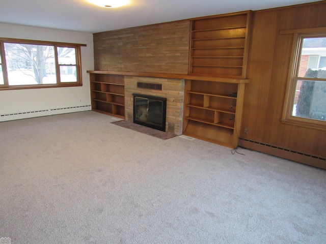 unfurnished living room featuring a baseboard heating unit, wooden walls, a fireplace, and light carpet