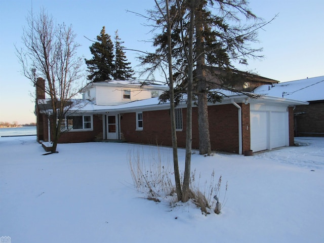 snow covered rear of property featuring a garage