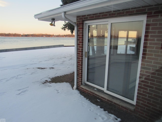 snow covered property entrance featuring a water view