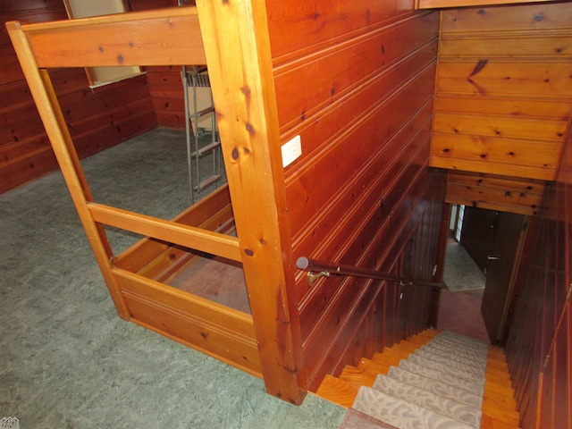 stairs featuring wood walls and carpet flooring