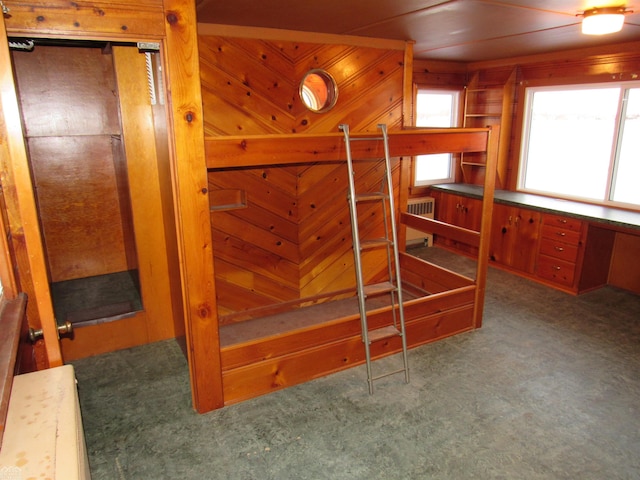 carpeted bedroom featuring radiator and wood walls