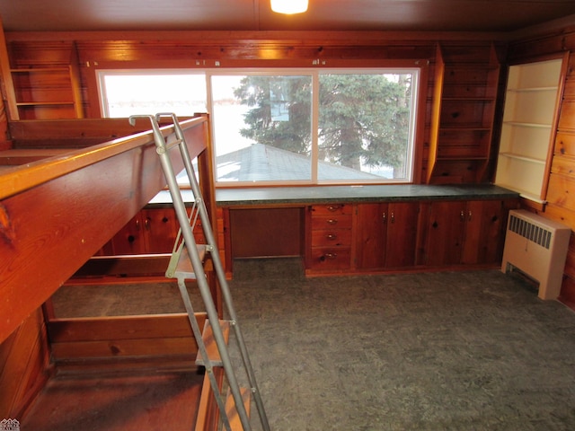 staircase with radiator heating unit, wood walls, and carpet flooring