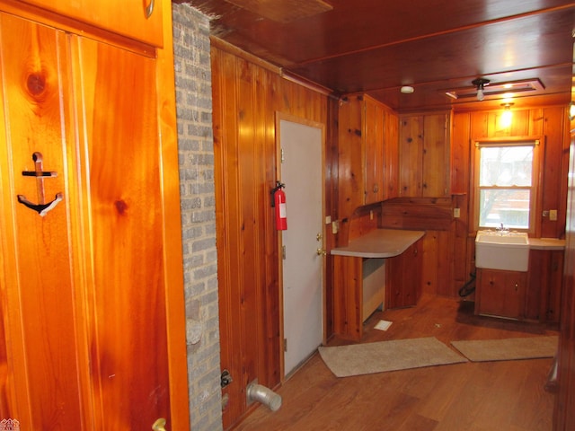 kitchen featuring ceiling fan, wood walls, sink, and wood-type flooring