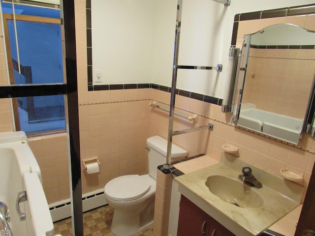 full bathroom with baseboard heating, toilet, vanity, tile walls, and tiled shower / bath