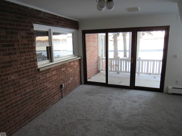 empty room featuring brick wall, a baseboard radiator, and carpet