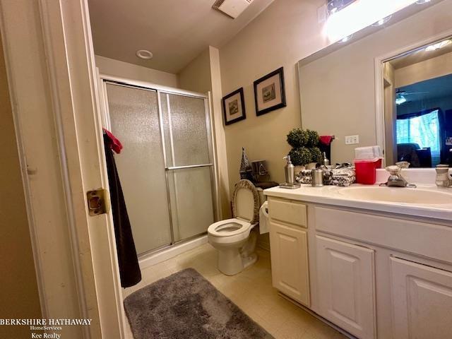 bathroom with toilet, vanity, and a shower with door