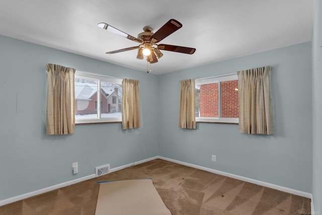 carpeted empty room featuring ceiling fan and a wealth of natural light