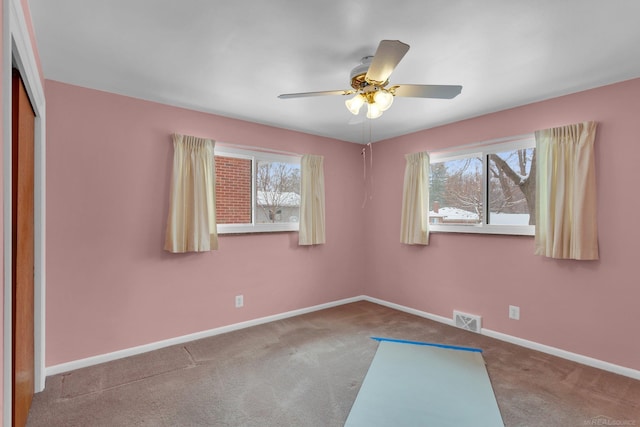 carpeted spare room featuring ceiling fan and a wealth of natural light