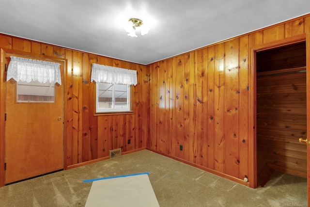 foyer entrance featuring carpet floors and wooden walls