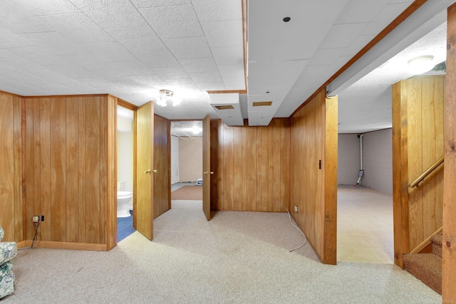 basement featuring light colored carpet and wood walls