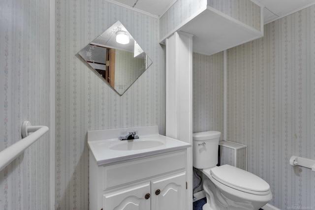 bathroom featuring toilet, ornamental molding, and vanity