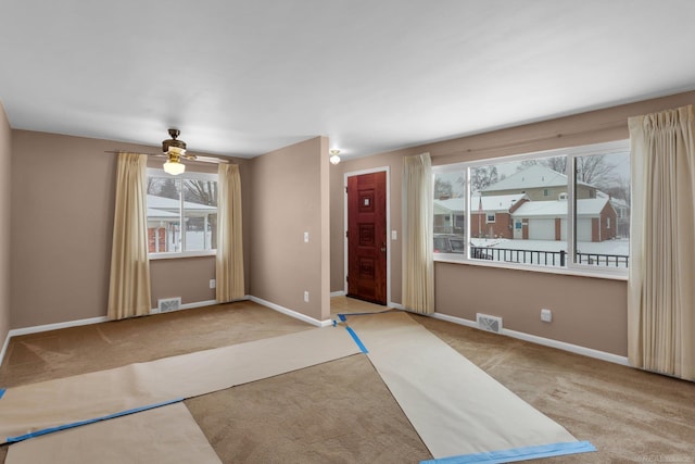 carpeted foyer entrance with ceiling fan and a healthy amount of sunlight