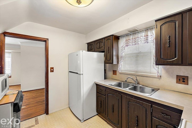 kitchen with dark brown cabinets, sink, and white appliances